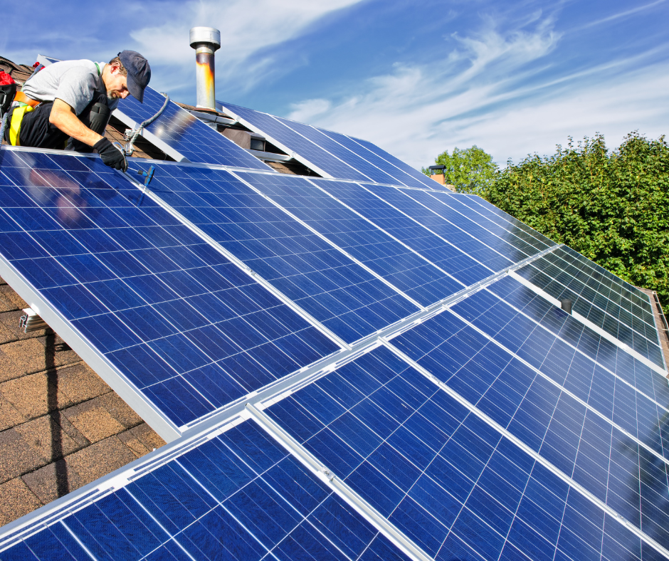 worker fitting solar panels on a roof