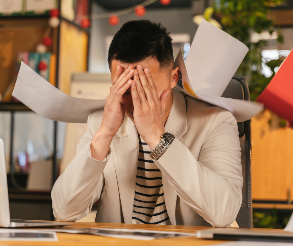 Man with head in hands while paper flies around him